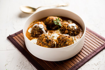 Malai Kofta is a Mughlai Speciality dish served in a bowl or pan over moody background. selective focus