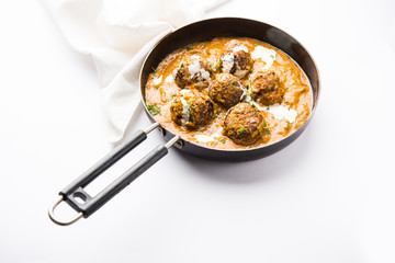 Malai Kofta is a Mughlai Speciality dish served in a bowl or pan over moody background. selective focus