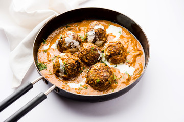 Malai Kofta is a Mughlai Speciality dish served in a bowl or pan over moody background. selective focus
