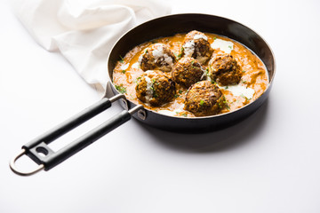 Malai Kofta is a Mughlai Speciality dish served in a bowl or pan over moody background. selective focus