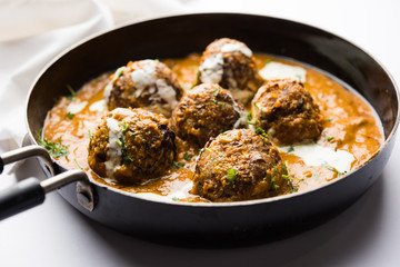 Malai Kofta is a Mughlai Speciality dish served in a bowl or pan over moody background. selective focus