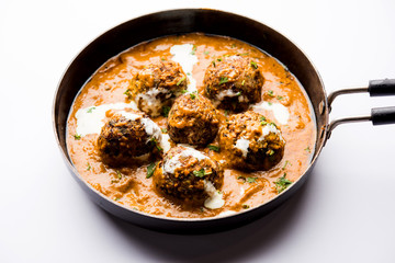 Malai Kofta is a Mughlai Speciality dish served in a bowl or pan over moody background. selective focus