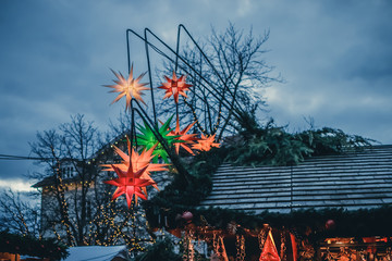 Star shaped christmas decorations hanging on a kiosk at a christmas market.