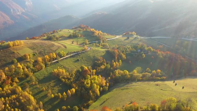 Aerial drone 4k view of autumn countryside mountain landscape with wooden houses, thatched roof and dirt road in Transylvania, Romania