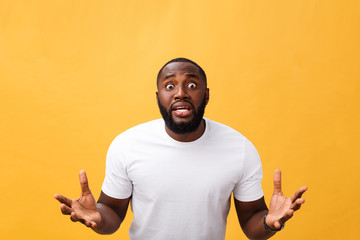 Portrait of african american man with hands raised in shock and disbelief. Isolated over yellow background.
