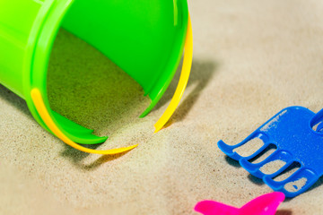 toys, childhood and summer concept - close up of bucket and rake on beach sand