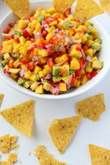 White bowl of fresh homemade mexican sauce, its nachos chips on white background from above.