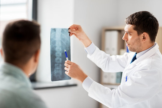medicine, healthcare and people concept - doctor showing x-ray to patient at medical office in hospital