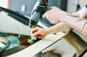 Man shaping the window tinting film with a heat gun. Professional window tinting services.