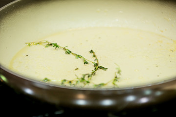 A branch of Majorana seasoning is fried in oil in a griddle in the kitchen. The aroma of herbs.