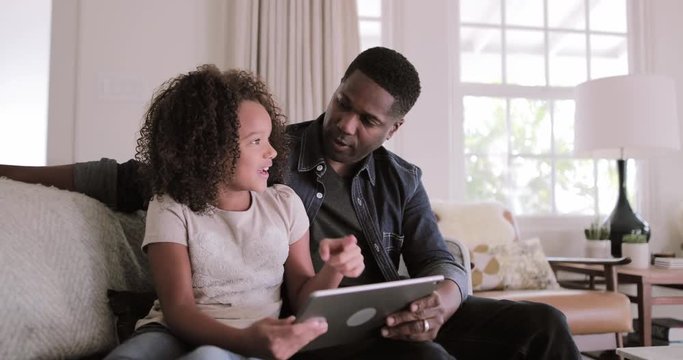 African American father and daughter using digital tablet together