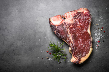 Dry aged beef steak t-bone on black slate background. 