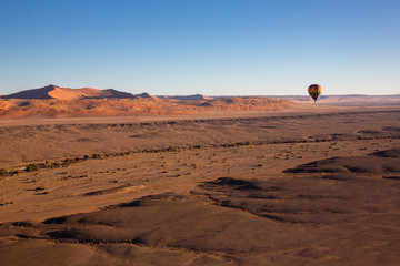 Sossusvlei. Colorful hot-air balloon flying over the high mountains in Namibia. High altitude.  Namibia, South Africa