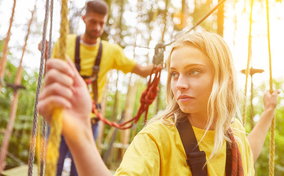 Frau lernt Klettern im Hochseilgarten oder Kletterwald