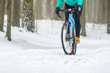 Cyclist on cyclocross bike trails in the snowy forest in winter. Downhill riding a snowy slope. Winter workout outdoors concept