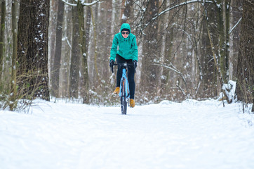 Obraz premium Rowerzysta na trasach rowerowych cyclocross w śnieżnym lesie zimą. Koncepcja treningu zimowego na zewnątrz