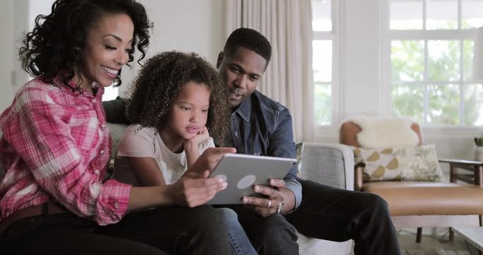 African American family watching video on digital tablet at home