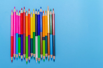 Collor wooden pencils in row isolated on bluebackground. Top view with copy space.