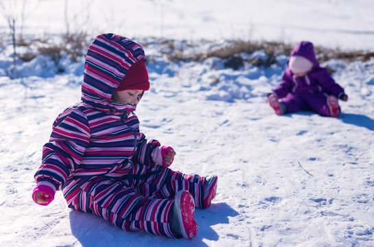 craying  two children in a  white snow in the warm suit siting  in the snow