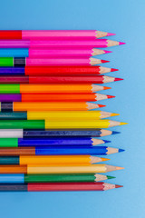 Collor wooden pencils in row isolated on bluebackground. Top view with copy space.