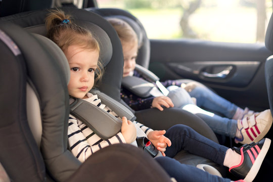 cute small twins in car seats in the car