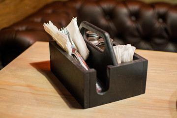 Wooden box for cutlery for a cafe. Selection of cutlery and spices on a wooden table.