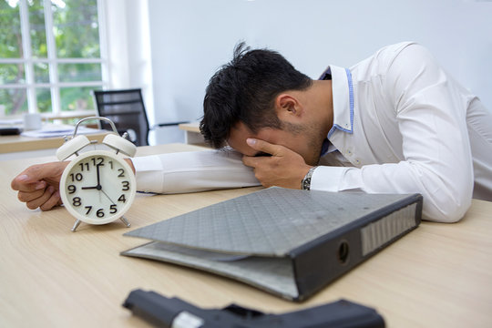 Businessmen are dismayed at business problems. Depressive, unhappy male wants to commit suicide. Businessman with pistol gun laying on a table. Watch, time, gun, chance, disappointment.