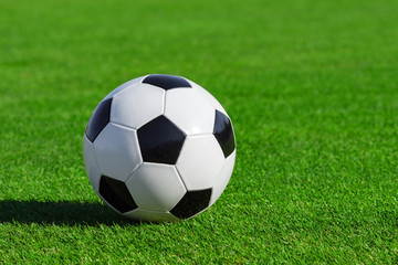 Classic soccer ball lies on the bright green grass on the football field at a sports stadium close-up in a large sports center for football players. Ready idea for your text and design