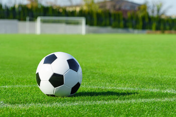 Classic soccer ball lies on the bright green grass on the football field in the designated area of the penalty area against the gate the sports stadium close-up in sports center for football players