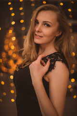 Portrait of Beautiful Woman in Lights. Fashion Dress and MakeUp. Christmas Santa. Elegant Lady in Red Dress over Christmas Tree Lights Background. Happy New Year.