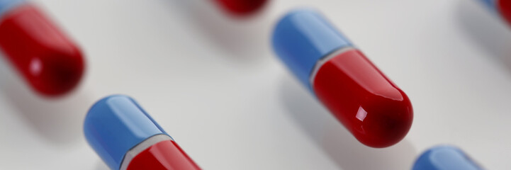 Pile of red and blue pills arranged in diagonal line on table
