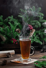 Steaming glass with tea on a dark christmas background.