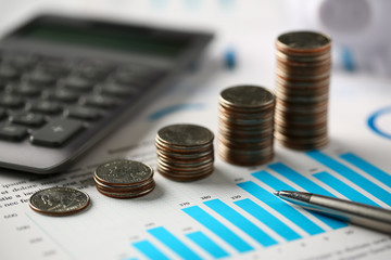 Pile of silver coins stand at financial graph papers