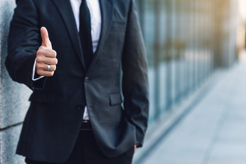Businessman showing thumb up  posing on background of office building