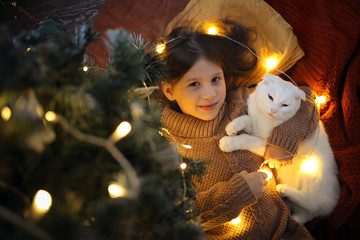 cat and girl under Christmas tree, gold and dark