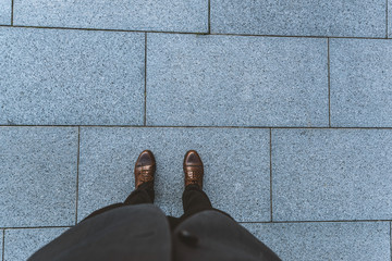 Outdoors in the city pavement. close-up of male legs in trousers and classic shoes.