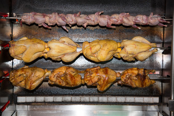 Roasted chickens in a row in a shop roaster