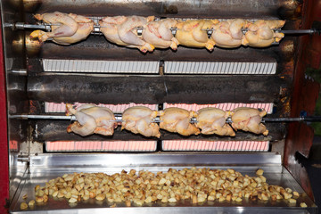 chickens cook in a roaster with potatoes on the market