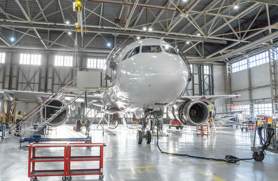 Commercial aircraft jet on maintenance of engine and fuselage check repair in airport hangar.