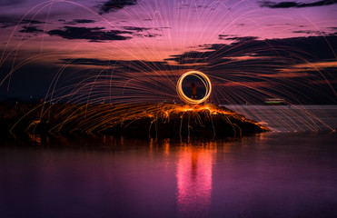 The beautiful fire dancer swing fire dancing show on the beach with dark clouds,dark sky background