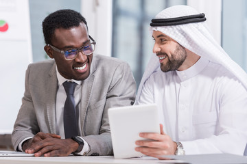 Multicultural business partners looking at digital tablet in modern office