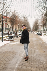 A young man turning around leaves in the city view in the city goes along the avenue. hipster man in winter city