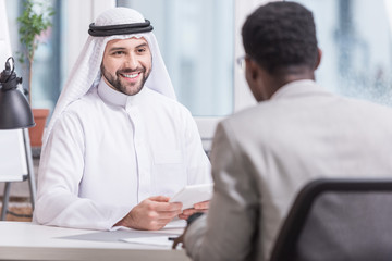 Arabian businessman smiling and holding digital tablet in office
