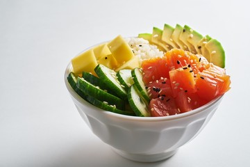 poke bowl with salmon, avocado, mango, rice, cucumbers, sprinkled with white and black sesame...