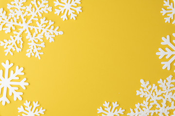 Christmas snowflake pattern with   frame copy space on yellow pastel  background. Flat lay. Minimal concept