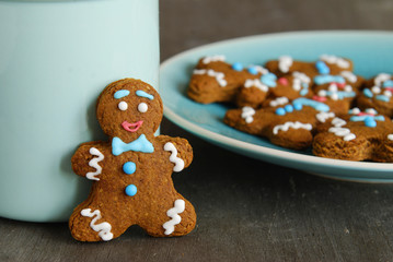 Christmas composition: Gingerbread man and blue cup on a dark wooden background.