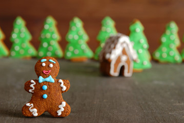 Christmas composition: gingerbread man against the background of a gingerbread house and gingerbread trees.