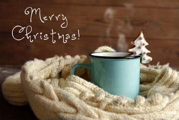 A blue cup with hot tea and a white knitted scarf on a dark