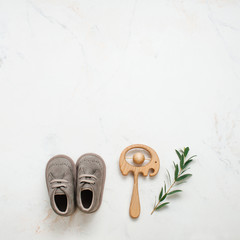 Newborn baby shoes and wooden beanbag on light marble background