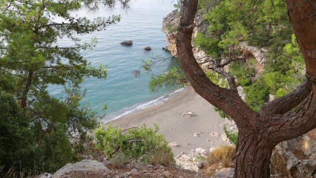 Beautiful morning seascape. Aerial top view of charming calm blue sea water, huge rocks and stones, green trees. Scenic summer marine background. Real time full hd video footage.